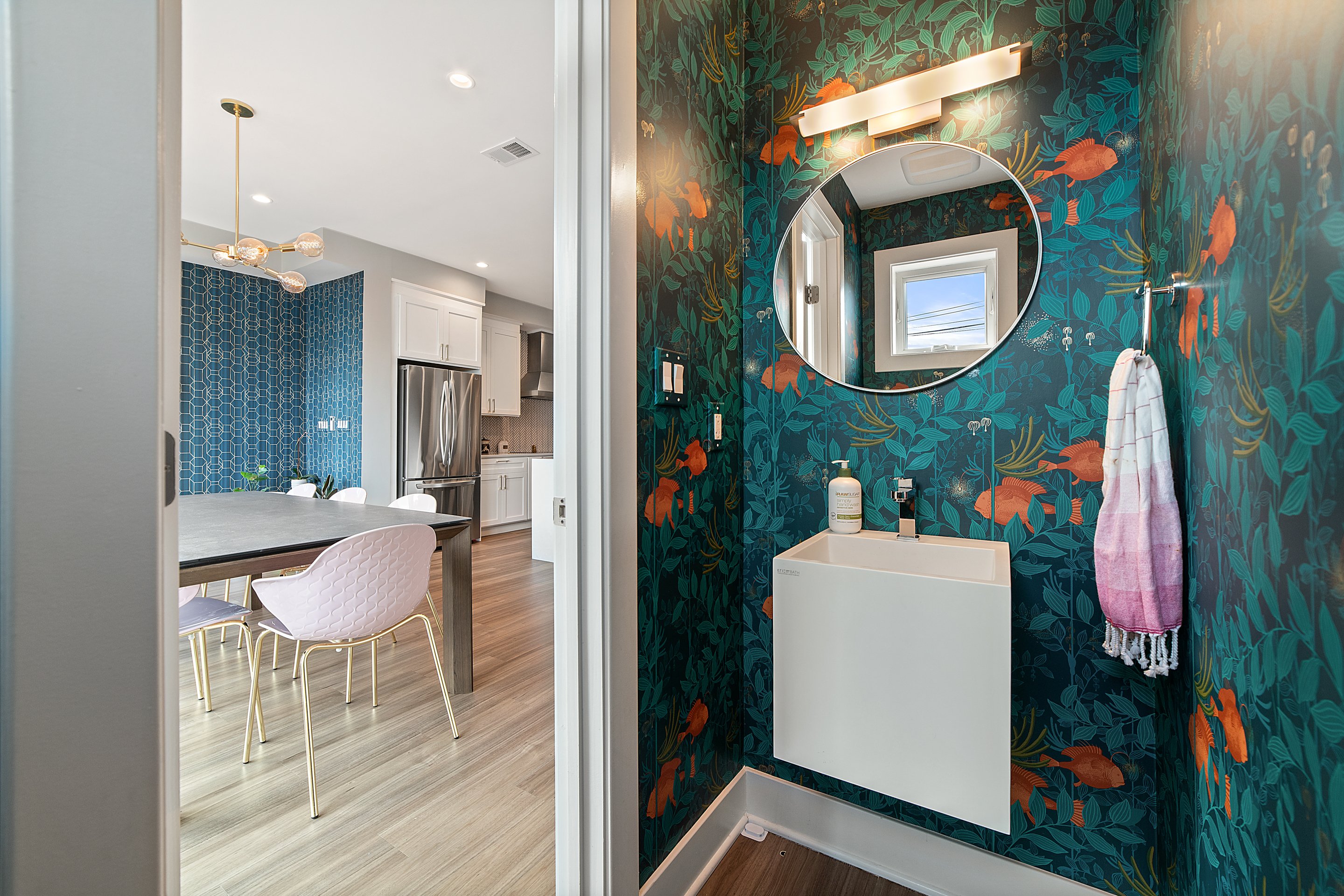 An elegant bathroom with a sleek white light figure and a sleek modern chandelier in the kitchen. Wilcox Electric DC