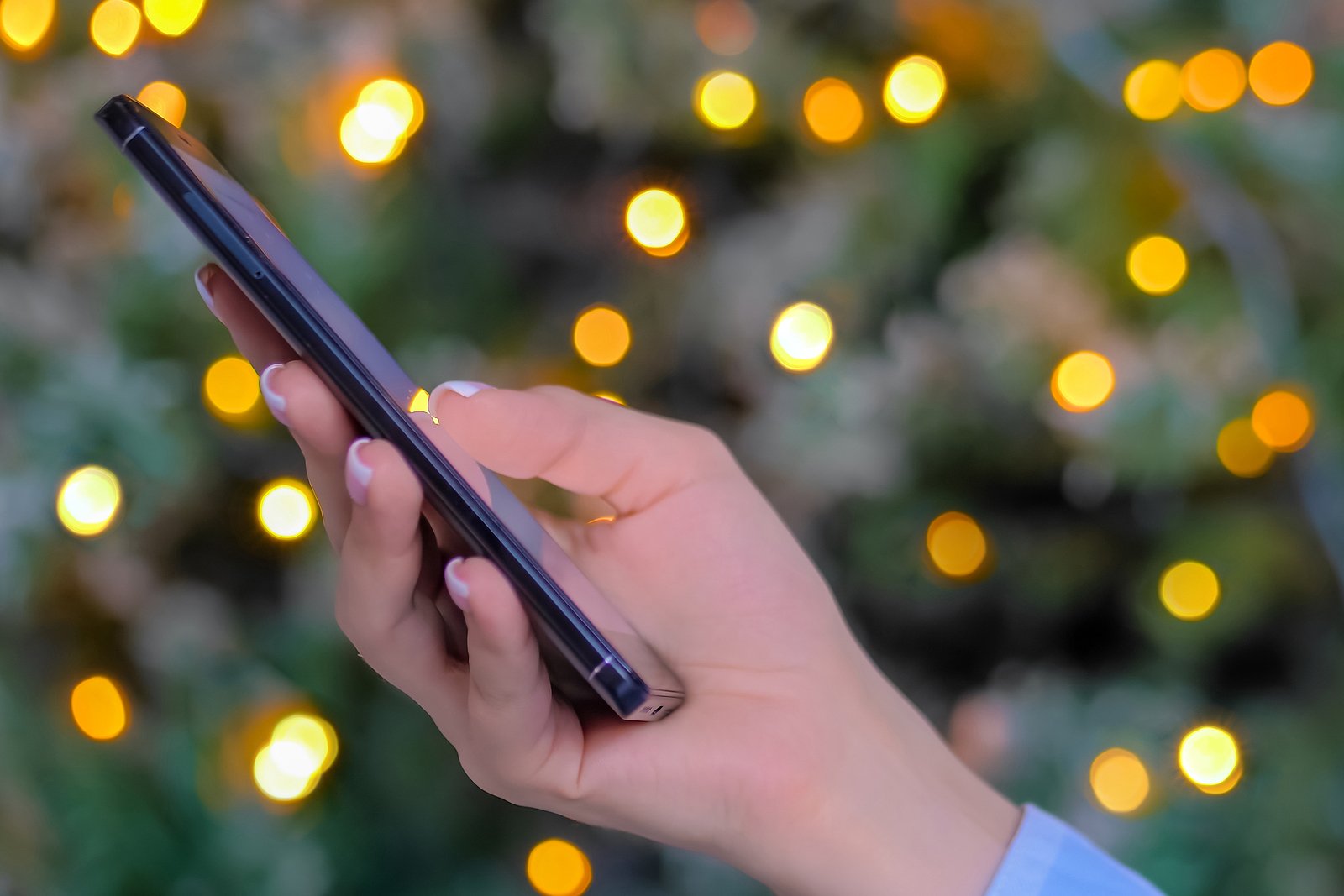 woman holds smart device with holiday lights in background Wilcox Electric DC