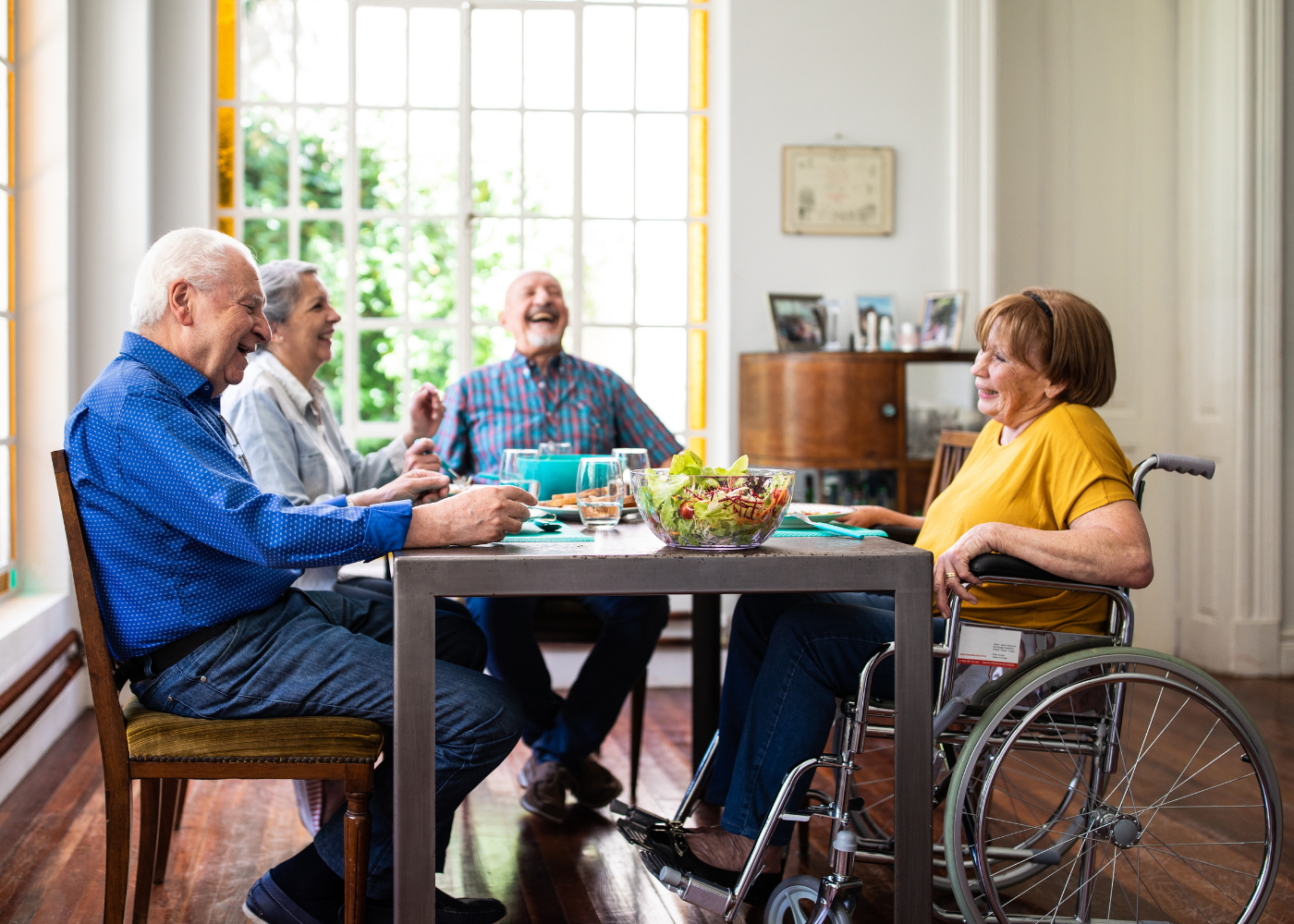Two elderly couples socializing over a meal, with one woman in a wheelchair Wilcox Electric DC