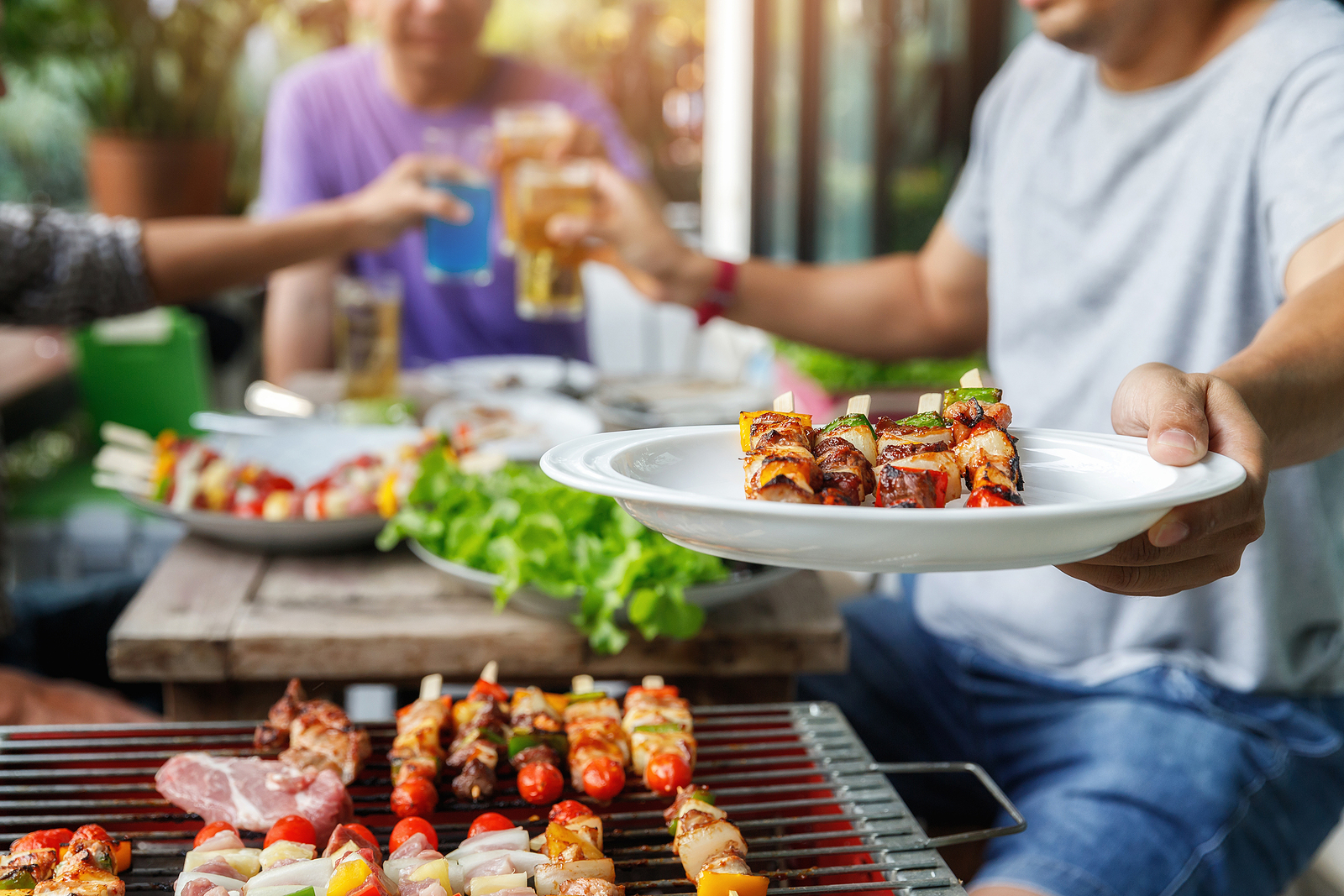 At an outdoor barbecue, a man holds a plate of delicious grilled vegetables and chicken. Wilcox Electric DC 